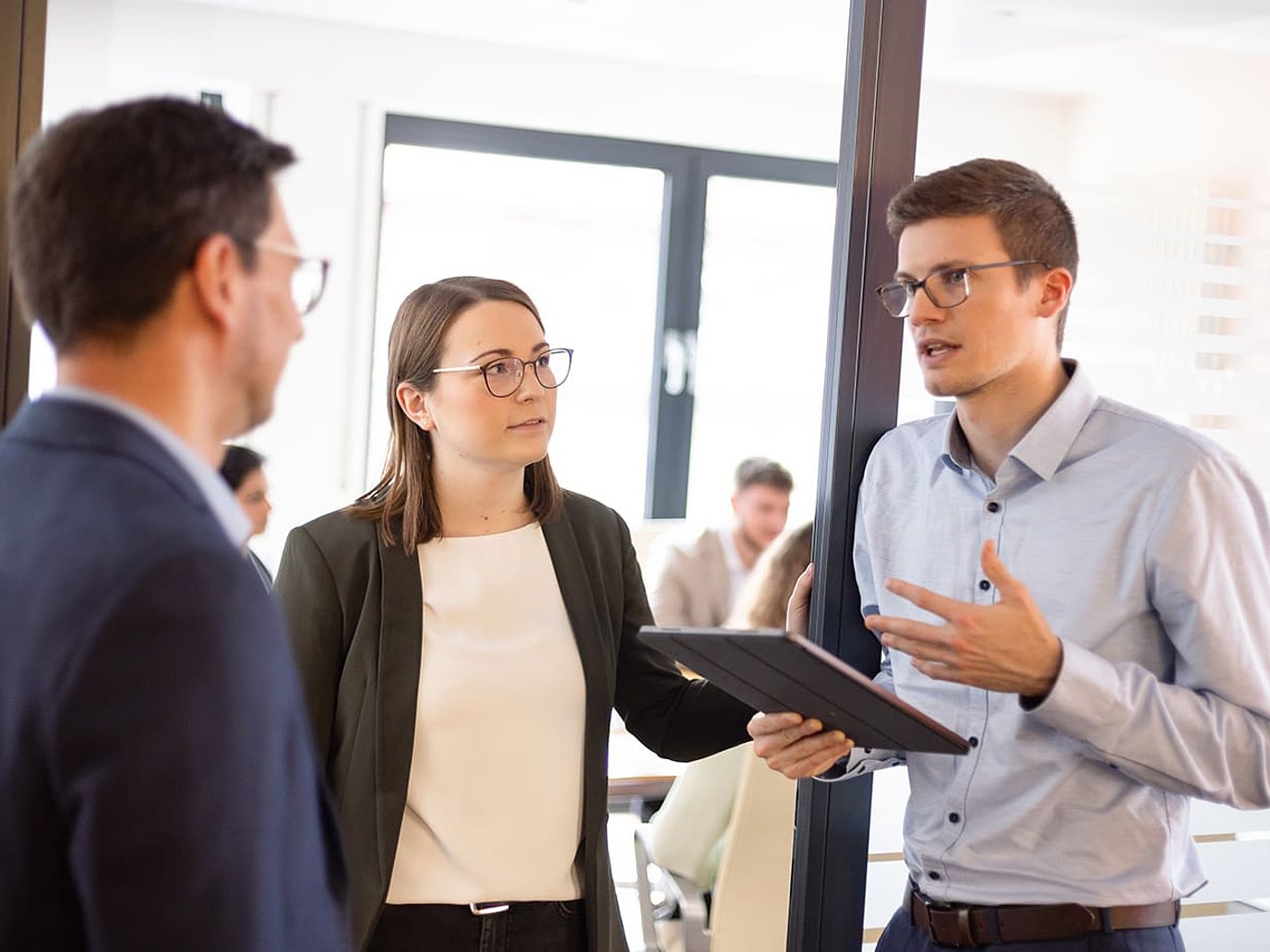 Drei junge Mitarbeitende stehen im Türrahmen im Office am Hafen und unterhalten sich.
